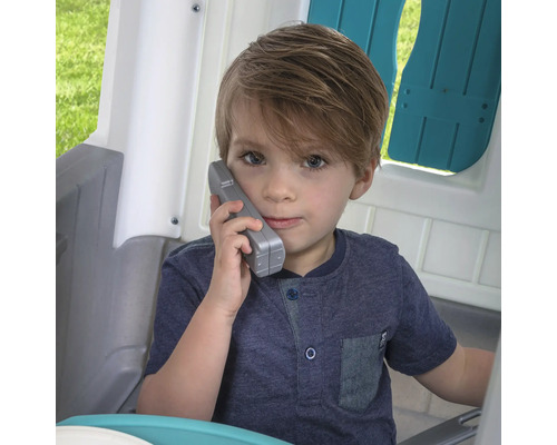 Junge telefoniert in einem Spielhaus