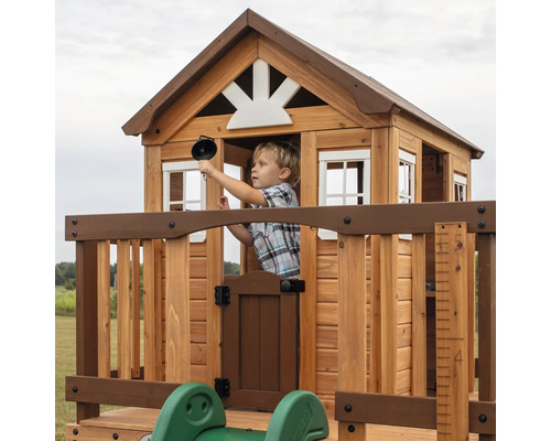 Kind spielt in einem Holzspielhaus mit Geländer und einer Glocke