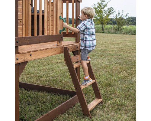 Junge klettert auf ein Holzspielhaus mit Leiter und Griff