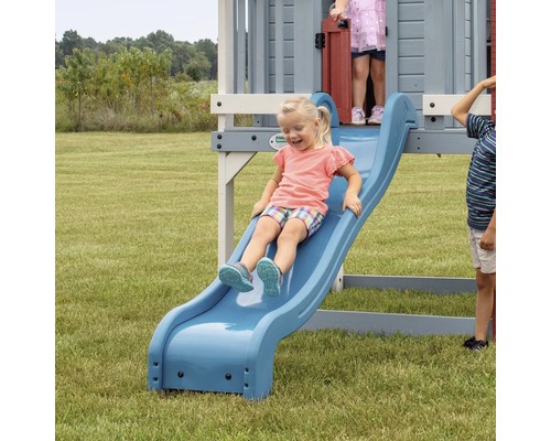 Mädchen rutscht auf einer blauen Rutsche eines Spielturms im Garten
