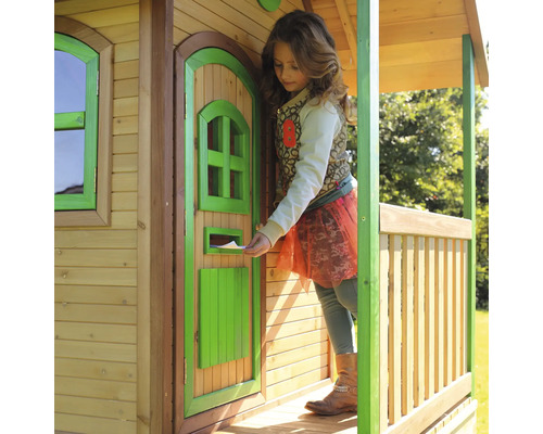 Kind steckt einen Brief in den Briefkasten eines Holzspielhauses
