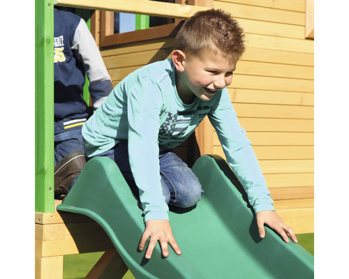 Junge rutscht auf einer grünen Rutsche eines Spielturms