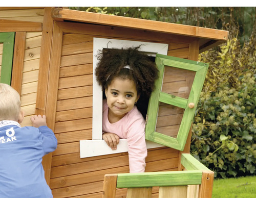 Kind spielt in einem Holzspielhaus mit Fenster
