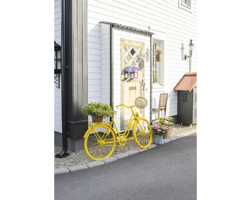 Dekoratives gelbes Fahrrad mit Blumen vor einem Haus.