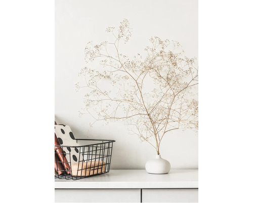 Dekorative getrocknete Blumen in Vase neben einem Metallkorb auf einem weißen Schrank