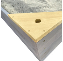 Detailansicht eines Sandkastens mit Holzabdeckung und Sand
