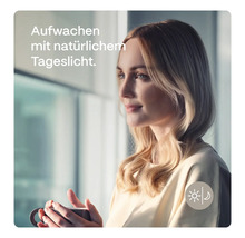 Frau mit Tasse vor einem Fenster mit Tageslicht