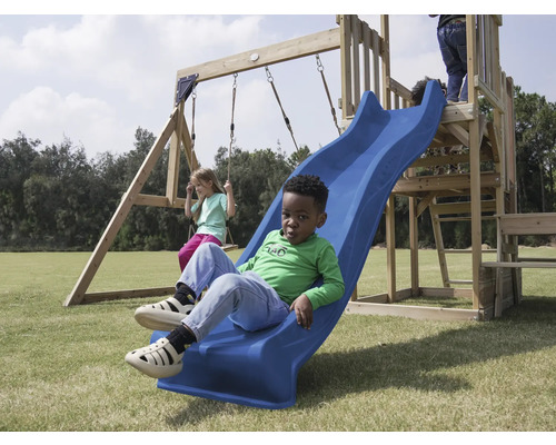 Kind rutscht auf einer blauen Rutsche eines Spielplatzes, während ein anderes Kind auf einer Schaukel schwingt.