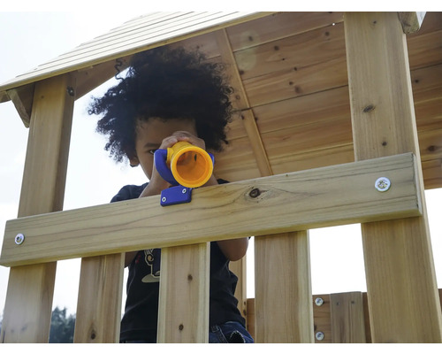 Kind spielt mit einem Spielzeugfernrohr in einem Holzspielhaus