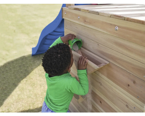 Kind schüttet Sand in eine Sandrinne an einem Spielturm