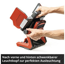 Ein Arbeiter verstellt den schwenkbaren Leuchtkopf einer roten und schwarzen Einhell Akku-Baustellenleuchte.