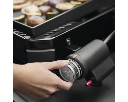 Nahaufnahme eines Gasgrills mit einer Hand, die den Regler bedient