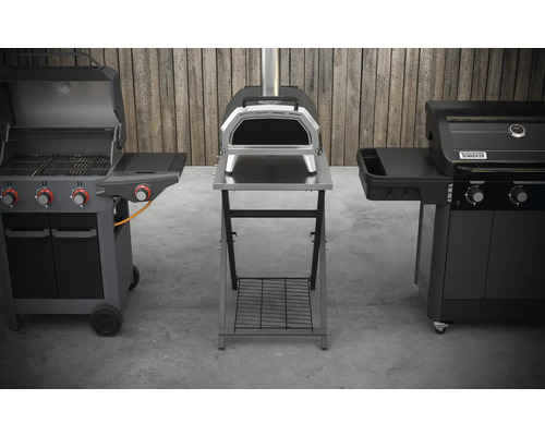 Drei verschiedene Grillgeräte im Außenbereich: Gasgrill, Pizzaofen und weiterer Grill.