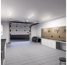 Garage mit Werkbank, Werkzeugwand, Reifen und geöffnetem Garagentor