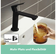 Schwarzer Wasserhahn mit Komfortzone füllt Glas mit Wasser im Waschbecken