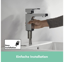 Person installiert einen verchromten Wasserhahn auf einem Waschbecken. Symbol für einfache Installation.