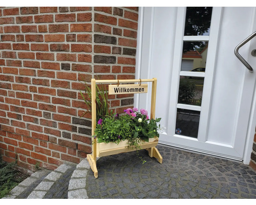 Holzblumenständer mit Willkommensschild vor einer Haustür