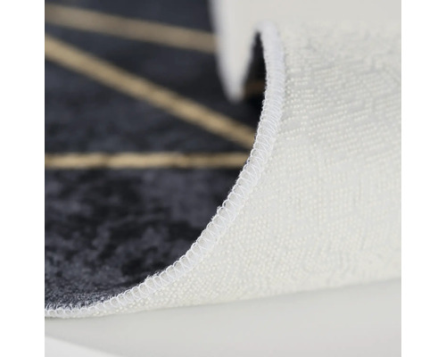 Detailansicht eines Teppichs mit geometrischem Muster und weißer Stoffkante.