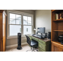 Büro mit Turmventilator, Schreibtisch und Regalen für eine organisierte Arbeitsumgebung.