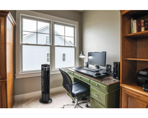 Büro mit Turmventilator, Schreibtisch und Regalen für eine organisierte Arbeitsumgebung.