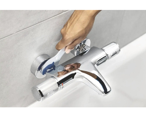 Person betätigt Badewannenarmatur aus Metall