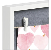 Detailansicht eines Bilderrahmens mit Fotos, die mit einer Wäscheklammer befestigt sind