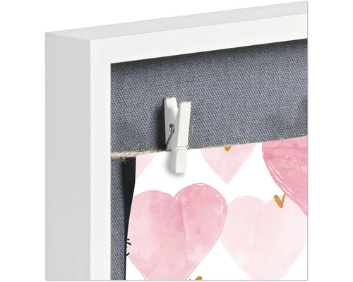 Detailansicht eines Bilderrahmens mit Fotos, die mit einer Wäscheklammer befestigt sind