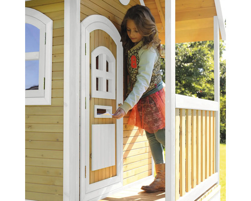 Mädchen steckt Brief in Briefkasten eines Holzspielhauses