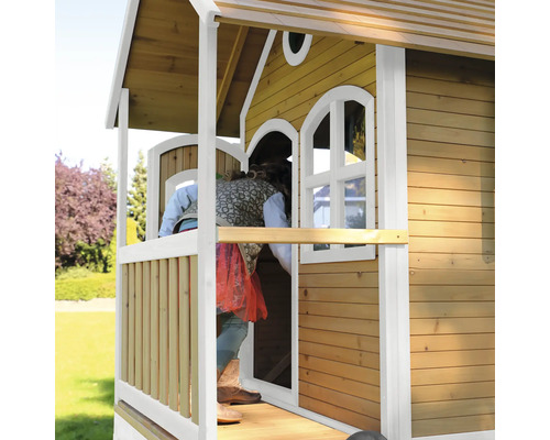 Kind betritt ein hölzernes Spielhaus mit Fenstern und Veranda