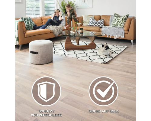 Wohnzimmer mit Ledercouch, Teppich, Glastisch und Holzboden. Symbol: Schützt vor Verschleiss. Symbol: Sicher auf Holz.