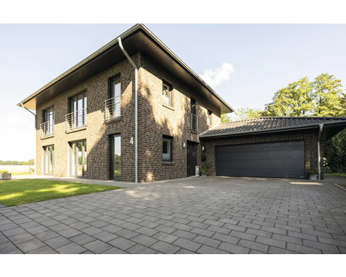 Ein zweistöckiges Backsteinhaus mit Garage und gepflasterter Auffahrt