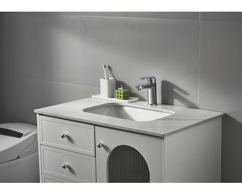 Waschtisch mit Waschbecken, Armatur und Badezimmeraccessoires vor grauer Wand