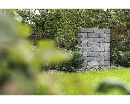 Gemauerte Gartensäule aus Steinblöcken neben einem Rasen