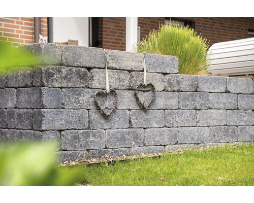 Graue Gartenmauer aus Betonsteinen mit zwei Herzdekorationen