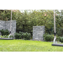 Garten mit Rasenfläche, bepflanzten Steinmauern und Schaukel