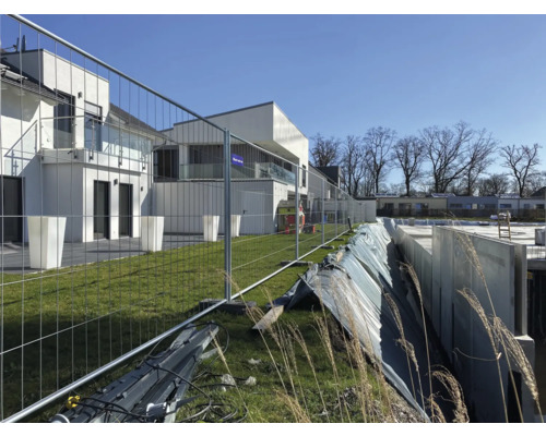 Baustelle mit Bauzaun und Rohbau eines Hauses