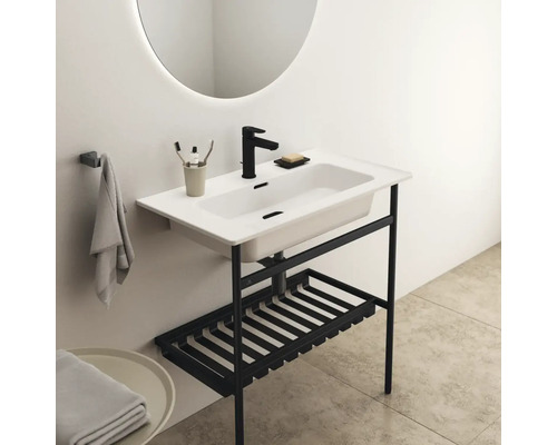 Waschtisch mit schwarzem Gestell, Aufbewahrung und rundem Spiegel im Badezimmer.
