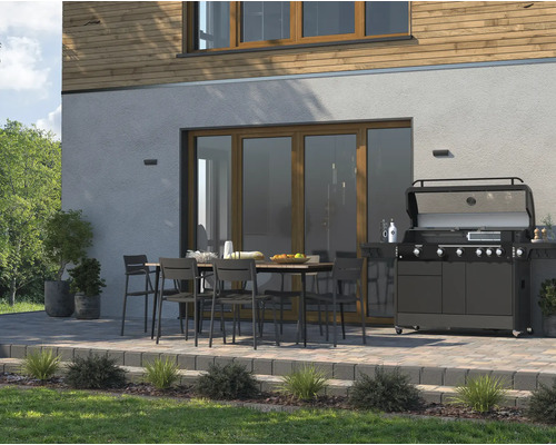 Terrasse mit Esstisch, Stühlen und Gasgrill vor einem Wohnhaus.