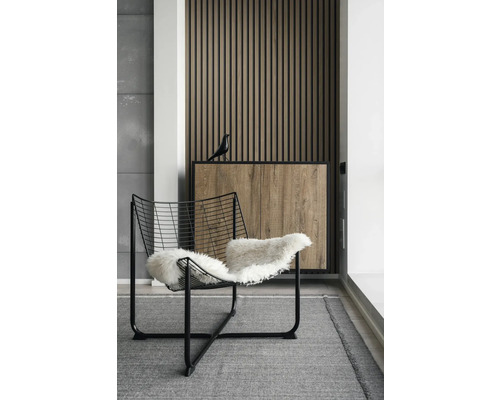 Innenraum mit Drahtsessel und Holzpaneelwand