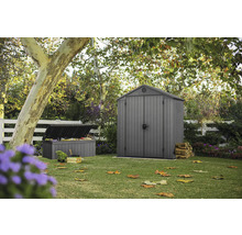 Gartenszene mit Gerätehaus, Gartenbox und Gartenwerkzeug auf einer Rasenfläche
