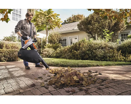 Mann benutzt einen Laubsauger von Stihl im Garten, um Laub zu entfernen.