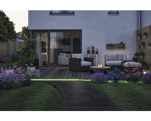 Stimmungsvoller Garten mit Lounge-Möbeln, Holzterrasse und beleuchtetem Weg