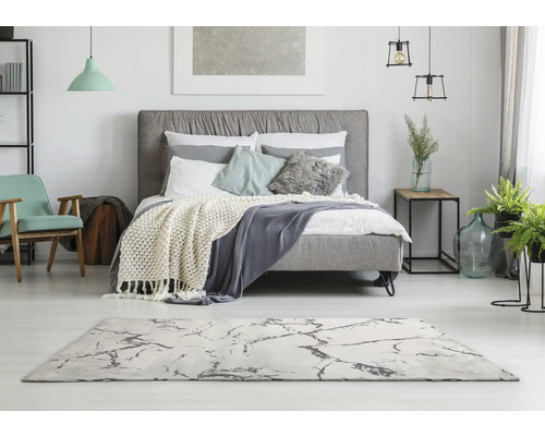 Helles Schlafzimmer mit Bett, Teppich und Dekorationen für eine freundliche Atmosphäre.