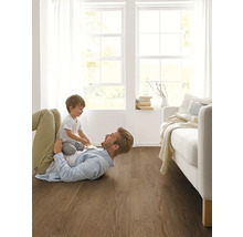 Vater und Kind spielen auf einem Bodenbelag aus Holz in einem hellen Wohnzimmer.