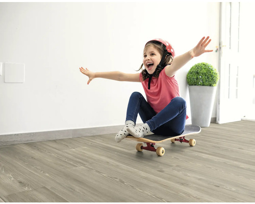 Mädchen mit Helm und Skateboard auf hellem Holzboden