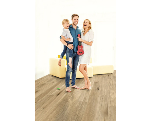 Familie mit Kind und roter Ukulele auf Holzboden in hellem Raum
