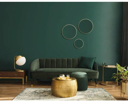 Wohnzimmer mit Sofa, Couchtisch und Dekorationen vor grüner Wand