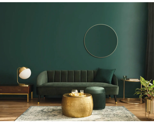 Wohnzimmer mit Sofa, Couchtisch und Dekoration vor einer grünen Wand