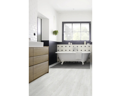 Badezimmer mit freistehender Badewanne, Waschtisch und Fenster für ein helles Ambiente.