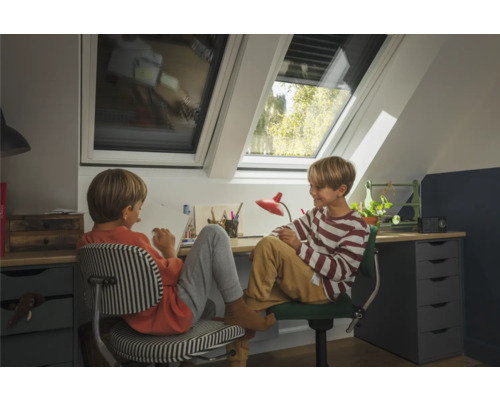 Zwei Kinder sitzen an einem Schreibtisch mit Dachfenstern für natürliches Licht.